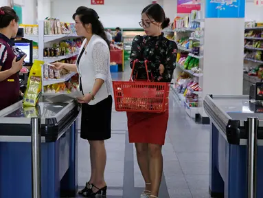 Dua wanita berada di kasir di supermarket di Pyongyang, Korea Utara (12/9). Banyak produk dalam negeri terlihat di rak-rak supermarket tersebut sebagai bagian dari upaya membangun ekonominya dan meningkatkan standar hidup nasional. (AP Photo/Kin Cheung)