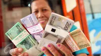 Warga menunjukkan uang pecahannya yang telah ditukar pada layanan mobil kas keliling di Lapangan IRTI, Monas, Jakarta, Kamis (2/7). Sebanyak 15 bank membuka gerai penukaran uang pecahan hingga 15 Juli mendatang. (Liputan6com/Helmi Afandi)