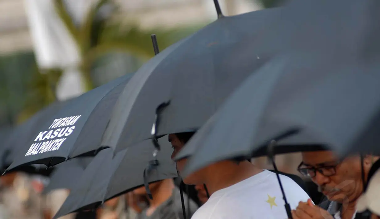 Massa yang memakai pakaian dan payung hitam, berdiri diam tanpa suara di depan Istana Merdeka, Jakarta, Kamis (12/6/14). (Liputan6.com/Miftahul Hayat)