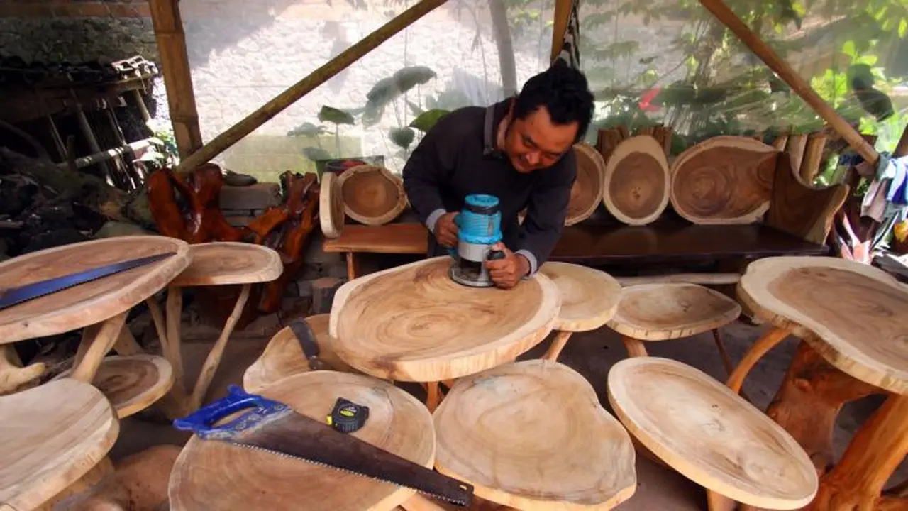 Hasyim, mengerjakan pembuatan furniture akar kayu. (Dhita/Liputan6.com)