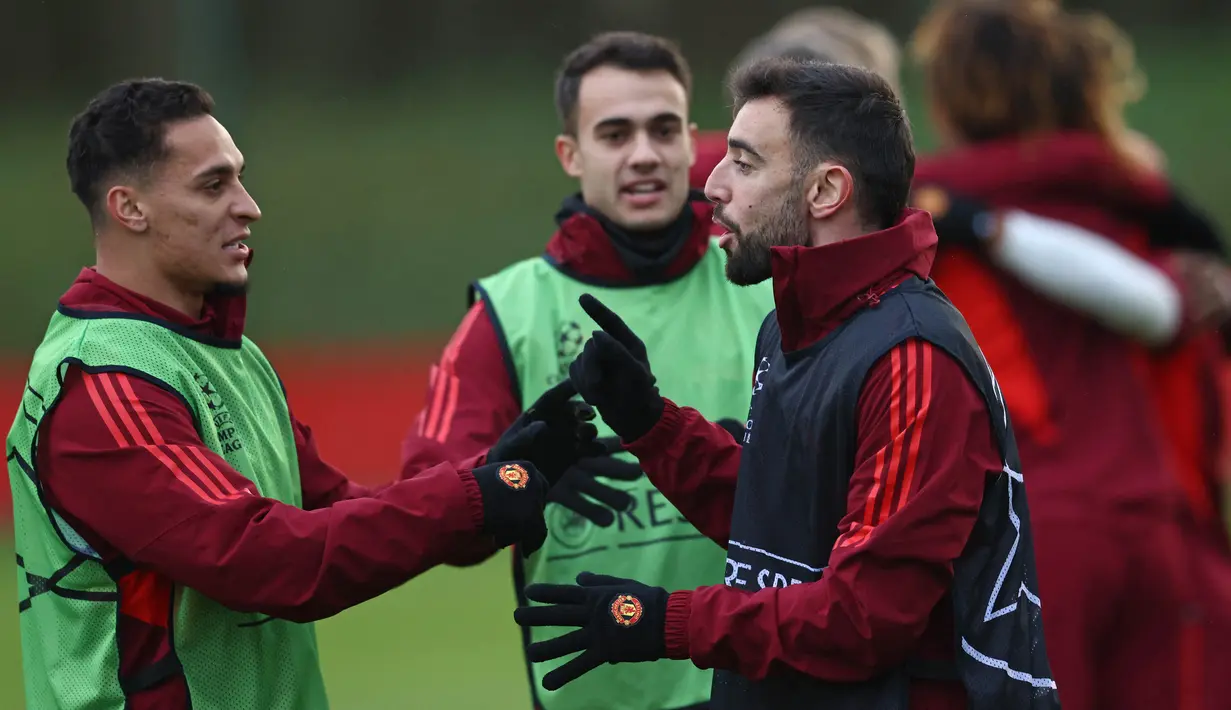 Pemain MU, Anthony (kiri) bercengkrama dengan Bruno Fernandes, dalam sesi latihan yang berlangsung di Carrington, Manchester, Selasa (12/12/2023) dini hari WIB. (AFP/Darren Staples)