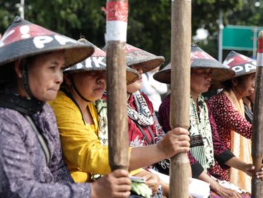 Sejumlah petani Pegunungan Kendeng menabuh lesung saat menggelar aksi di depan Istana Merdeka, Jakarta, Rabu (12/4). Mereka meminta Pemerintah untuk menghentikan pembangunan dan pabrik semen di Pegunungan Kendeng. (Liputan6.com/Faizal Fanani)