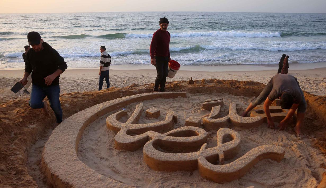 Seniman Palestina, Yazeed Abu Jarad, yang mengungsi dari Beit Lahia, membuat patung pasir dengan pesan ucapan "Selamat Datang, Ramadan" di sepanjang pantai di Khan Younis, selatan Gaza pada 17 Februari 2026. Tampak dalam foto, warga membantu seniman Palestina, Yazeed Abu Jarad, saat ia membuat patung pasir dengan pesan ucapan "Selamat Datang, Ramadan" di sepanjang pantai di Khan Younis, selatan Gaza pada 17 Februari 2026. (Bashar Taleb/AFP)
