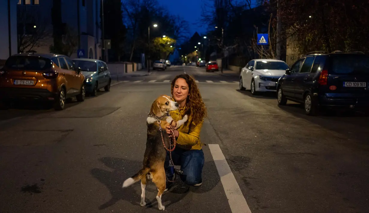 Catalina Gherghel (34) berpose dengan anjingnya Ziggy Stardust  (7) di Bucharest (29/3/2020). Undang-undang militer, yang disahkan pemerintah Rumania untuk mengurangi penyebaran virus corona, menyatakan berjalan bersama anjing adalah salah satu  kegiatan yang masih diizinkan. (AFP/Andrei Pungovschi)