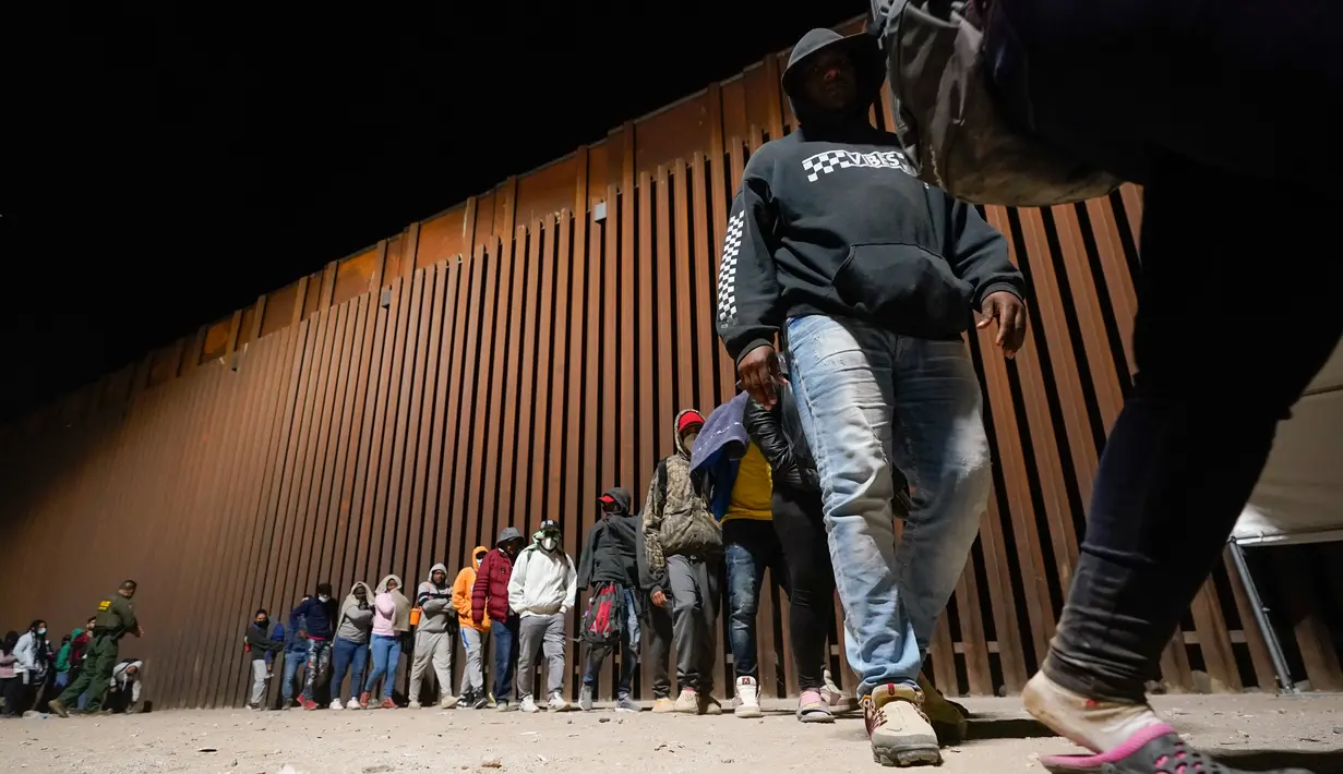 Sekelompok imigran, sebagian besar dari Kuba, berbaris untuk naik bus setelah melintasi perbatasan dari Meksiko dan menyerah kepada pihak berwenang untuk mengajukan suaka di dekat Yuma, Arizona, Amerika Serikat, 3 November 2022. Meski tercatat rekor masuknya imigran di perbatasan Amerika Serikat-Meksiko dan kekurangan pekerja di Amerika Serikat, para ahli percaya kebijakan imigrasi Amerika Serikat akan tidak berubah setelah pemilu paruh waktu nanti. (AP Photo/Gregory Bull)