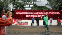 Warga berfoto di depan karangan bunga untuk Basuki T Purnama dan Djarot Sjaiful Hidayat di Balai Kota Jakarta, Selasa (25/4). Karangan bunga tersebut terus bertambah berisi simpati warga kepada Ahok-Djarot pascapilkada DKI 2017. (Liputan6/Johan Tallo)