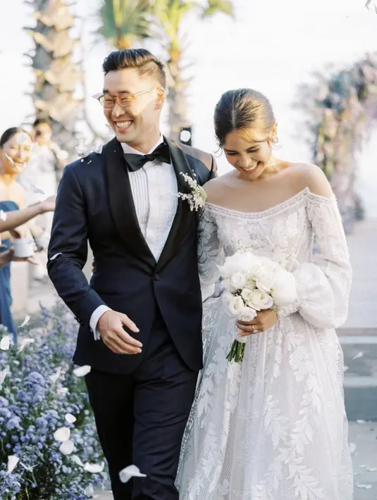 <p>Maudy Ayudan nampak mengenakan gaun putih indah strapless di bagian dada dan lengan puff karya desainer Hian Tjen. Sedangkan sang suami gagah dengan suit hitam dari Wong Hang Tailor. Dipadukan heels putihnya. @maudyayunda</p>