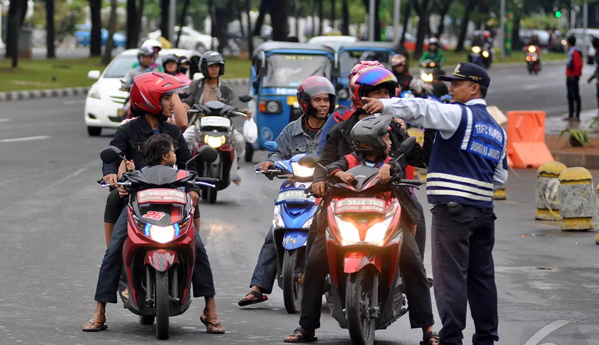 Petugas Dinas Perhubungan DKI Jakarta menunjukkan arah kepada para pemotor untuk tidak melewati Jalan Merdeka Barat, Jakarta, Kamis (1/1/2015). ( Liputan6.com/Miftahul Hayat)