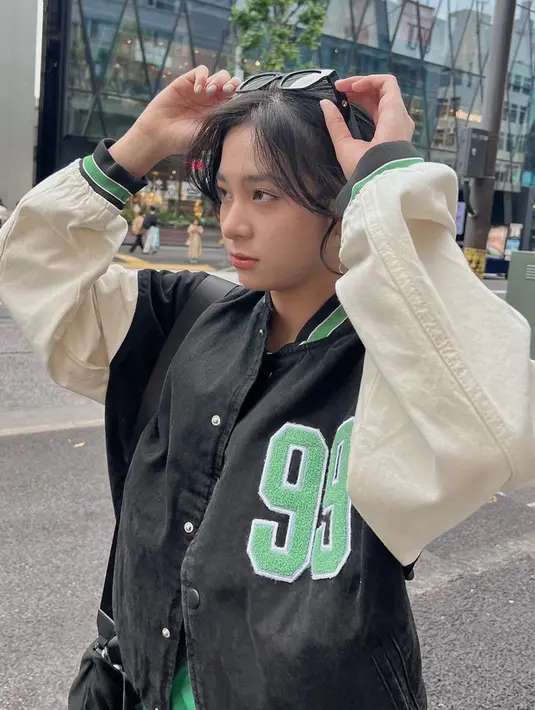 Jaket baseball sangat cocok dikenakan oleh member JKT48 yang jadi center Flying High ini. Ia terlihat kece dengan outfit seperti itu ditambah aksesoris kacamata yang ia kenakan. Zee yang cantik kece ini berhasil bikin para penggemarnya terpesona. (Liputan6.com/IG/@jkt48.zee)