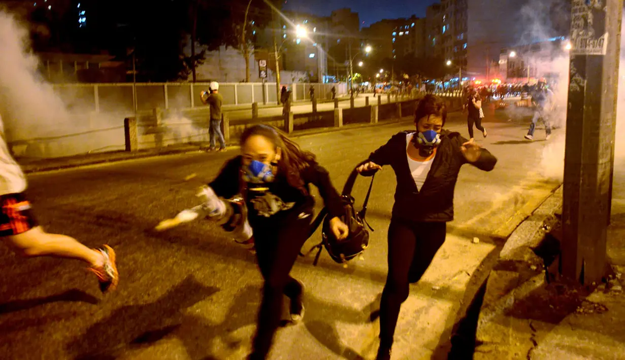 Polisi anti huru hara terpaksa menembakkan gas air mata untuk membubarkan massa aksi yang melakukan unjuk rasa anti Piala Dunia 2014 di sekitar Stadion Stadion Maracana, Rio de Janeiro, Brasil, (15/6/2014). (REUTERS/Lucas Landau)