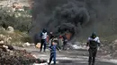Demonstran Palestina membakar ban dan menutup jalan saat melakukan aksi di desa Kfar Qaddum, Palestina (16/3). Mereka menolak pengakuan Presiden AS Donald Trump atas Yerusalem sebagai ibu kota Israel. (AFP Photo/Jaafar Ashtiyeh)
