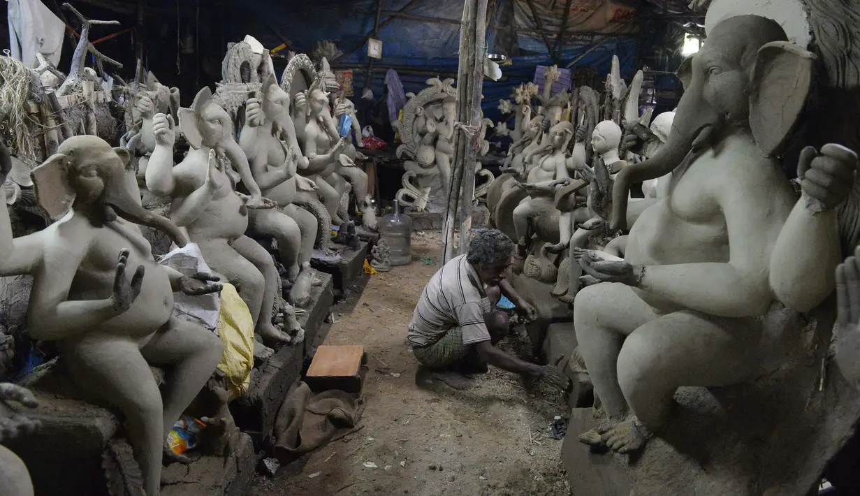 Perajin membuat patung Dewa Ganesha di sebuah bengkel di pinggiran Hyderabad, India, Rabu (18/8/2021). ​Patung ramah lingkungan yang dibuat jelang perayaan Ganesh Chaturthi tersebut dibuat dari lumpur, serat rami, dan bambu untuk mengurangi polusi air. (NOAH SEELAM/AFP)