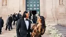 Sean Gelael tampil necis dengan tuxedo hitam yang membuatnya terlihat gagah. Sementara itu, Hana Malasan mengenakan dress berwarna abu-abu yang dipadukan dengan outer cokelat syal bulu, memberikan kesan anggun namun tetap simpel. Penampilan mereka begitu serasi sebagai pasangan kekasih. (Liputan6.com/IG/@gelaelized)