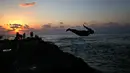 Seorang pria melompat saat berenang di Laut Mediterania dari Corniche, atau promenade tepi laut  saat matahari terbenam pada hari terakhir musim panas, di Beirut, Lebanon (20/9). (AP Photo / Hussein Malla)