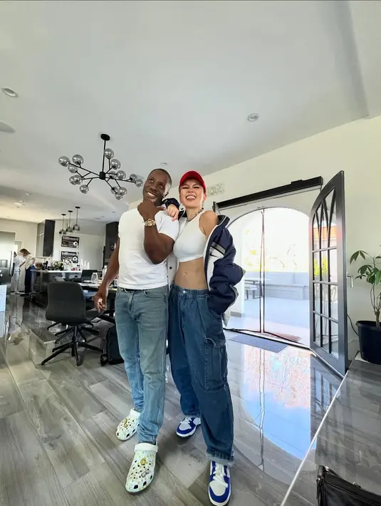 Agnez Mo pamer body goals dengan padukan crop top putih dan oversized cargo jeans. Oversized baseball jacket dan sneakers jadi sentuhan boyish [@agnezmo]
