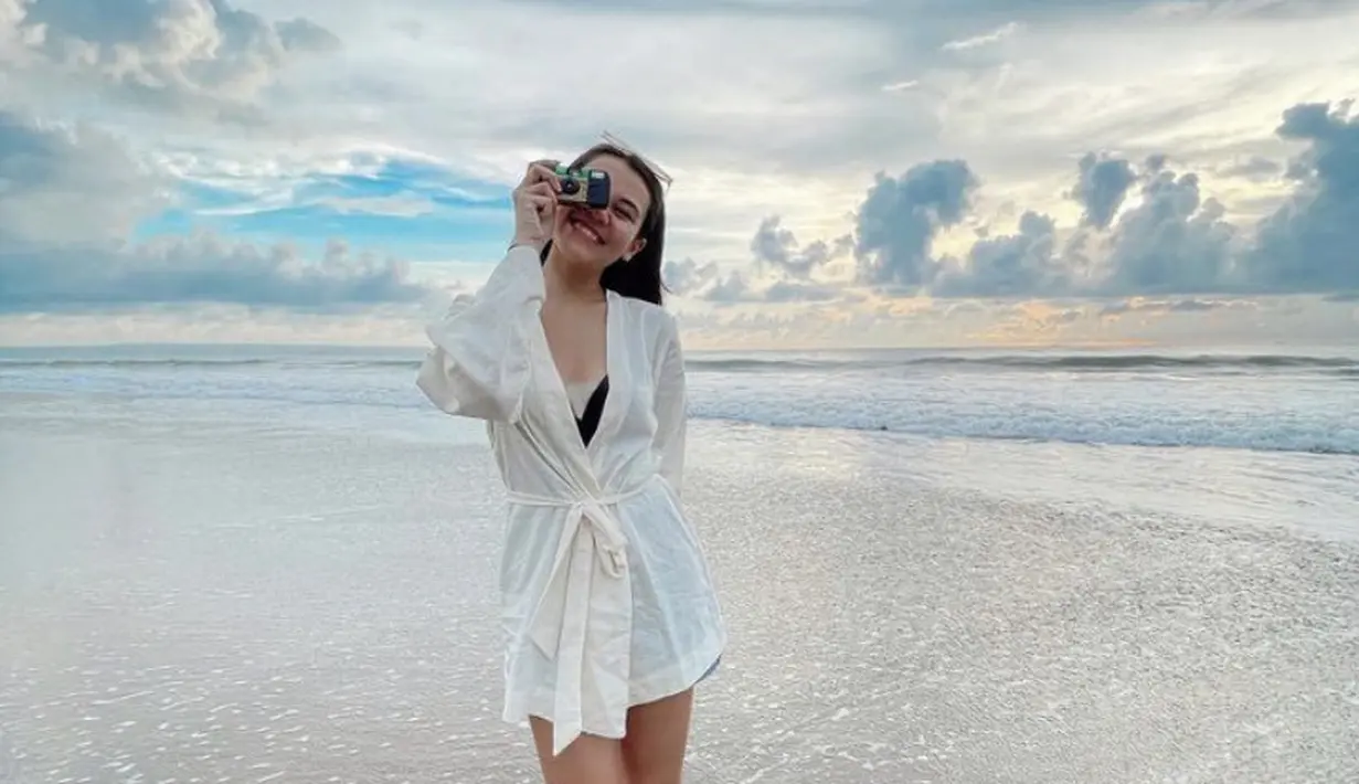 Kimono putih dengan belt dan inner hitam, dikenakan Aaliyah saat bermain di pantai. Dipadukan dengan sandalnya. [@aaliya.massaid]