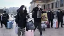 Penumpang membawa tas mereka ke pintu masuk stasiun kereta api Beijing di ibu kota China (7/1/2023). Ketika migrasi tahunan dimulai dengan orang-orang yang kembali ke kampung halaman mereka untuk perayaan Tahun Baru Imlek. (AFP/Wang Zhao)