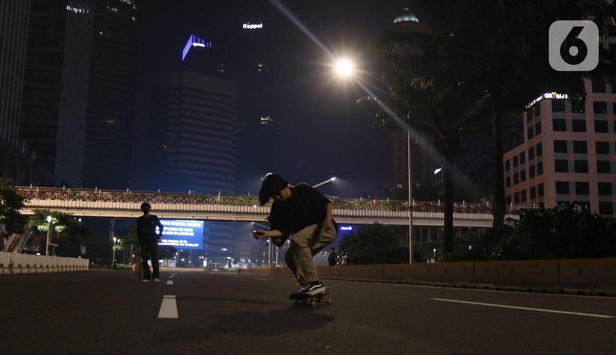 Warga bermain skateboard di jalan lengang kawasan Sudirman, Jakarta, Rabu (12/5/2021) malam. Polda Metro Jaya memberlakukan crowd free night untuk mencegah kerumunan takbir keliling di malam Idul Fitri 1442 yang berlaku mulai pukul 22:00 malam ini. (Liputan6.com/Herman Zakharia)