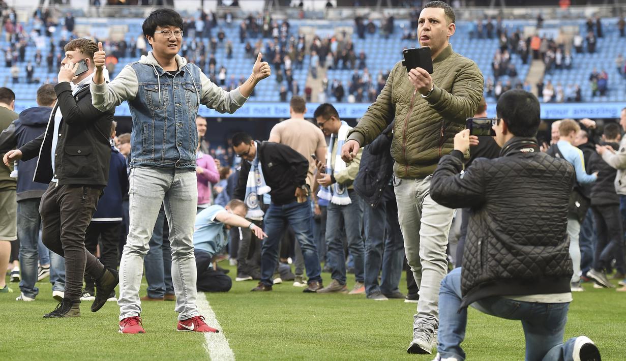 Saat turun ke lapangan Fans Manchester City melakukan sesi foto dan berjalan santai di rumput Etihad Stadium, Manchester, (22/4/2018). Manchester City menang 5-0. (AFP/Paul Ellis)