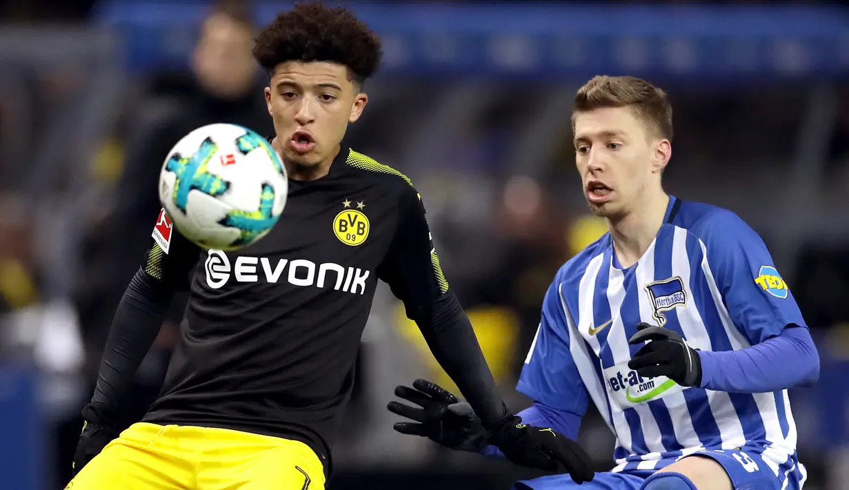 Pemain Borussia Dortmund, Jadon Sancho berebut bola dengan pemain Hertha Berlin, Mitchell Weiser dalam lanjutan Bundesliga di Olympiastadion Berlin, Sabtu (20/1). Borussia Dortmund hanya mampu bermain imbang 1-1 melawan Hertha Berlin. (AP/Michael Sohn)