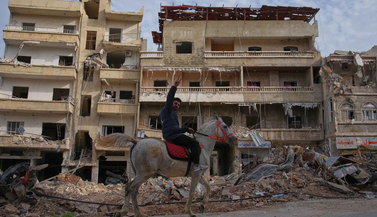 Seorang pria menunggang kuda melewati lokasi bangunan yang hancur akibat serangan udara Israel, di Jibchit, Lebanon Selatan, Jumat 17 April 2026, setelah gencatan senjata antara Israel dan Hizbullah. (AP Photo/Hassan Ammar)