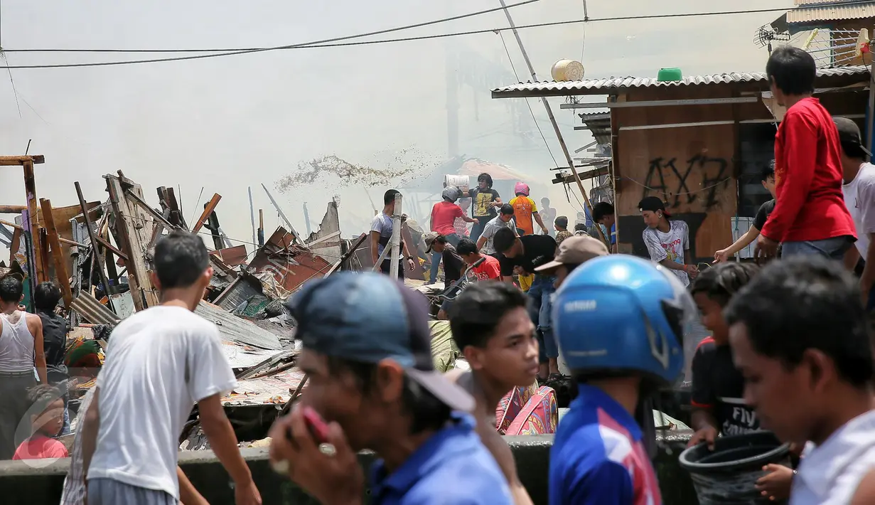 Warga bergotong-royong memadamkan api  saat kebakaran melanda pemukiman di Kampung Bandan, Ancol, Jakarta, Selasa (26/1). Lebih dari 27 mobil pemadam dikerahkan untuk menjinakkan api yang membakar bangunan semi permanen itu. (Liputan6.com/Faizal Fanani)