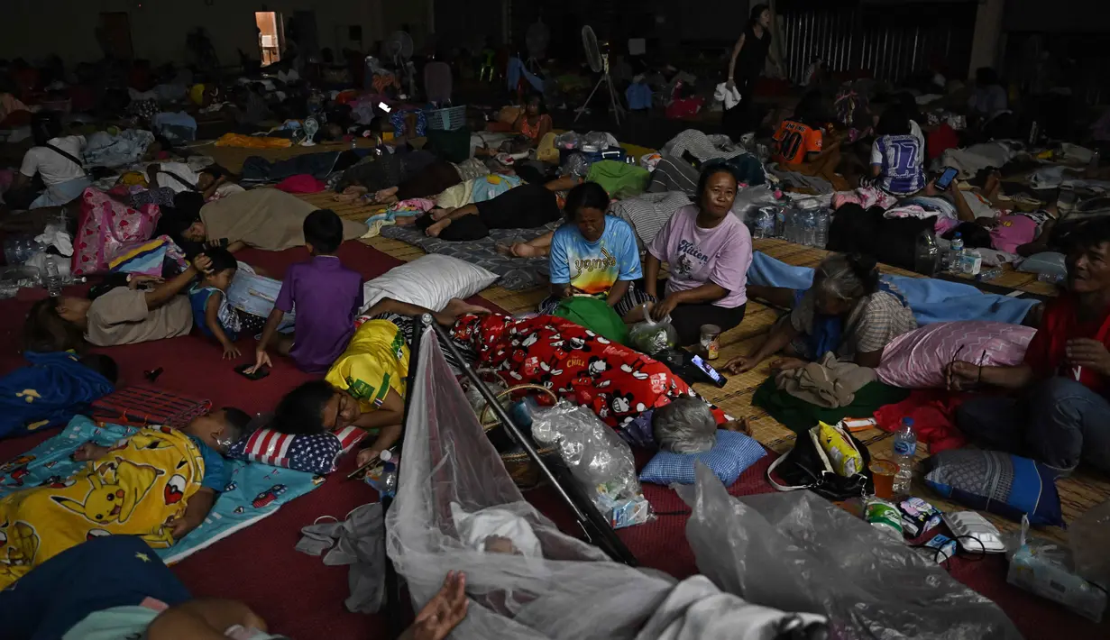 Imbas baku tembak antara militer Thailand dan Kamboja di wilayah sengketa perbatasan kedua negara pada Kamis pagi (24/7/2025), ratusan orang termasuk anak-anak dan orang tua mengungsi sementara di salah satu aula Universitas Surindra Rajabhat, di provinsi perbatasan Thailand, Surin. (Lillian SUWANRUMPHA/AFP)