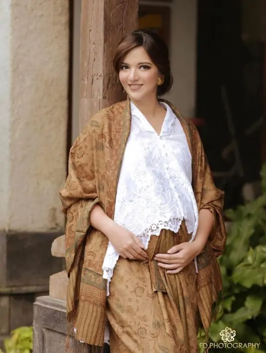 Nia Ramadhani cukup simple mengenakan kebaya putih yang dipadukan selendang cokelat, sertasi dengan kain bawahannya.  (@ramadhaniabakrie)