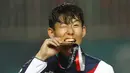 Penyerang Korea Selatan, Son Heung-min, menggigit mendali, usai menjuarai Asian Games dengan mengalahkan Jepang di Stadion Pakansari, Jawa Barat, Sabtu (1/9/2018). (AP/Bernat Armangue)