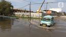 Sebuah angkutan umum (angkot)  melintasi banjir rob di kawasan Pelabuhan Perikanan Samudera Nizam Zachman, Muara Baru, Jakarta, Sabtu (6/11/2021). Banjir rob tersebut disebabkan karena naiknya permukaan air laut. (Liputan6.com/Herman Zakharia)