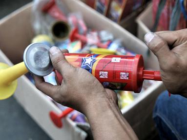 Pedagang memainkan salah satu terompet berbahan plastik yang dijualnya di kawasan Pasar Gembrong, Jakarta, Minggu (29/12/2019). Berbeda pada tahun sebelumnya, penjualan terompet plastik jelang perayaan malam Tahun Baru 2020 lebih marak dibandingkan terompet kertas. (merdeka.com/Iqbal Nugroho)