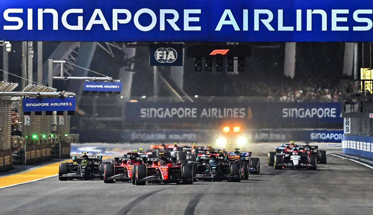 Pembalap tim Scuderia Ferrari, Carlos Sainz (tengah depan) memimpin para pembalap saat melakukan start balapan F1 GP Singapura 2023 di Marina Bay Street Circuit, Singapura, Minggu (17/9/2023) malam WIB. (AFP/Lillian Suwanrumpha)