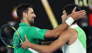 Novak Djokovic memberikan selamat kepada Carlos Alcaraz setelah berhasil juara Australian Open 2026 yang dilangsungkan di Melbourne Park pada (1/2/2026) sore WIB. (AFP/Martin Keep)