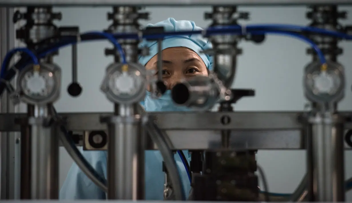 Foto pada 30 November 2018 menunjukkan pekerja berdiri di belakang mesin di Pabrik Kosmetik Sinuiju, kota perbatasan Korea Utara dengan China. Pabrik yang didirikan pada 1949 itu adalah basis produksi kosmetik berskala besar di Korea Utara. (Ed JONES/AFP)