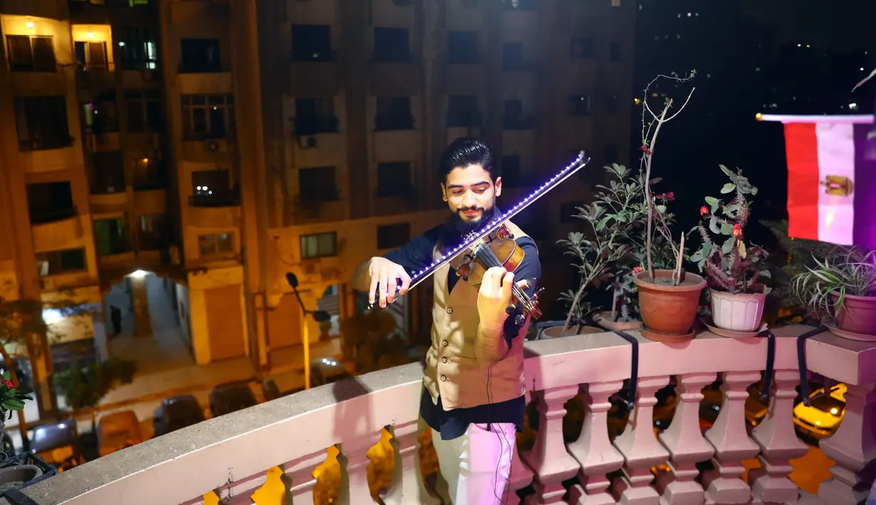 Pemain biola asal Mesir Mohammed Adel membawakan konser biola dari atas balkon di Kairo, pada 31 Maret 2020. Setiap malam, pemain biola itu menampilkan konser langsung dari balkonnya untuk menghibur para tetangganya selama jam malam nasional yang diberlakukan akibat COVID-19. (Xinhua/Ahmed Gomaa)