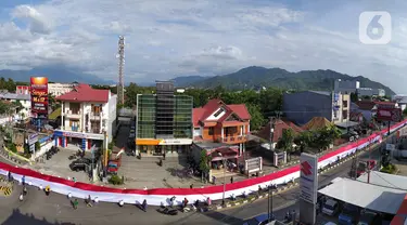 Pelajar SMA membentangkan bendera Merah Putih sepanjang 2,3 kilometer di Jalan Panjaitan dan Jalan Nani Wartabone, Gorontalo, Kamis (23/1/2020). Acara tersebut dilakukan untuk mengenang 78 tahun Hari Patriotik. (Liputan6.com/Arfandi Ibrahim)