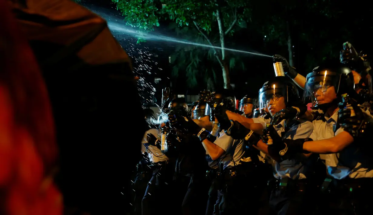 Polisi menyemprotkan cairan merica ke arah pengunjuk rasa saat demonstrasi menjadi ricuh di Hong Kong, Minggu (6/10). Kericuhan terjadi setelah massa terlibat deadlock selama delapan jam dengan aparat keamanan yang menjaga lokasi. (REUTERS/Tyrone Siu)