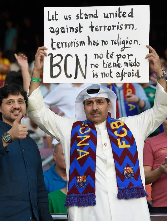 Penonton membawa kertas bertuliskan kalimat dukungan untuk korban serangan teror di laga pekan pertama Liga Spanyol antara Barcelona melawan Real Betis, Minggu (20/8). Seluruh orang di stadion memberikan tribut kepada para korban. (LLUIS GENE/AFP)
