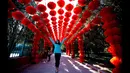Seorang wanita berpose di bawah lentera kertas, merayakan Tahun Baru Cina, di Ditan Park, Beijing (18/2/2015). Tahun Baru Imlek pada 19 Februari akan menyambut Tahun Domba. (Reuters /Kim Kyung-Hoon)