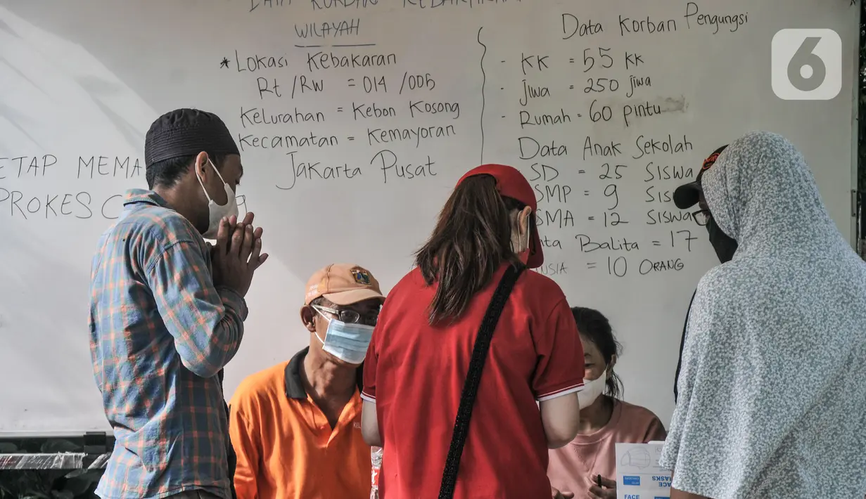 Aktivitas petugas saat menerima bantuan swadaya dari masyarakat di dekat papan informasi jumlah korban kebakaran di SDN 09 Kebon Kosong, Kemayoran, Jakarta, Selasa (31/8/2021). Ratusan pengungsi ditempatkan di dua ruang kelas yang dipisahkan berdasarkan jenis kelamin. (merdeka.com/Iqbal S. Nugroho)