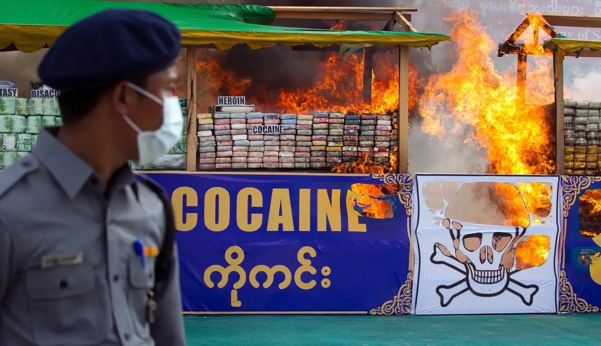 Seorang perwira polisi mengamati narkotika sitaan yang dibakar dalam acara pemusnahan pada Hari Antinarkoba Sedunia, di Yangon, Senin (26/6). Myanmar membakar opium, heroin, dan kokain senilai sekitar US$385 juta, setara Rp5,1 miliar. (AP Photo/Thein Zaw)