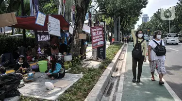 Warga korban gusuran Kampung Bayam mendirikan tenda darurat saat menggelar aksi di depan Balai Kota, Jakarta, Senin (5/12/2022). Dengan membawa terpal dan perabotan rumah tangga, puluhan korban gusuran Kampung Bayam kembali membangun tenda darurat di depan Balai Kota untuk menuntut PT Jakarta Propertindo (JakPro) segera menyerahkan kunci hunian Kampung Susun Bayam (KSB) serta memberikan harga sewa yang murah. (merdeka.com/Iqbal S. Nugroho)