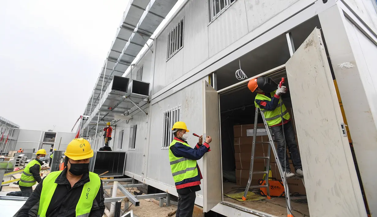 Pekerja China bekerja di lokasi pembangunan Rumah Sakit Huoshenshan (Gunung Dewa Api) di Wuhan, provinsi Hubei, Minggu (2/2/2020). Rumah sakit ini adalah salah satu dari dua fasilitas khusus yang dibangun untuk membantu mengatasi wabah Virus Corona tersebut. (Photo by STR / AFP)