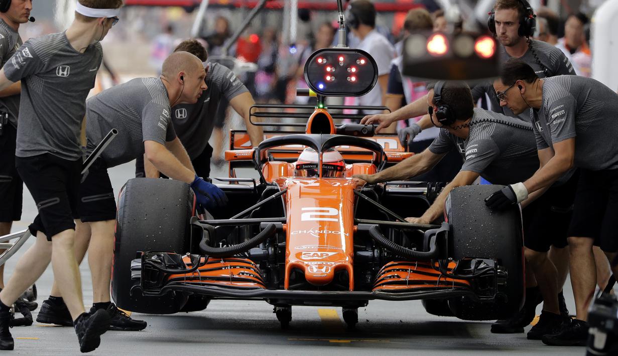 Kesibukan tim mekanik McLaren saat melihat kondisi mobil pebalap Stoffel Vandoorne di pit lane pada sesi latihan bebas F1 GP Singapura, Marina Bay City Circuit, (15/9/2017). (AP/Wong Maye-E)