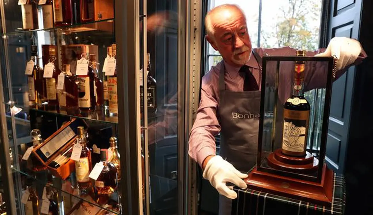Danny McIlwraith dari rumah lelang Bonhams memegang botol wiski terlangka dan paling berharga di dunia, The Macallan Valerio Adami 1926, pada lelang di Edinburgh, Skotlandia, Rabu (3/10). (Andrew Milligan/PA via AP)