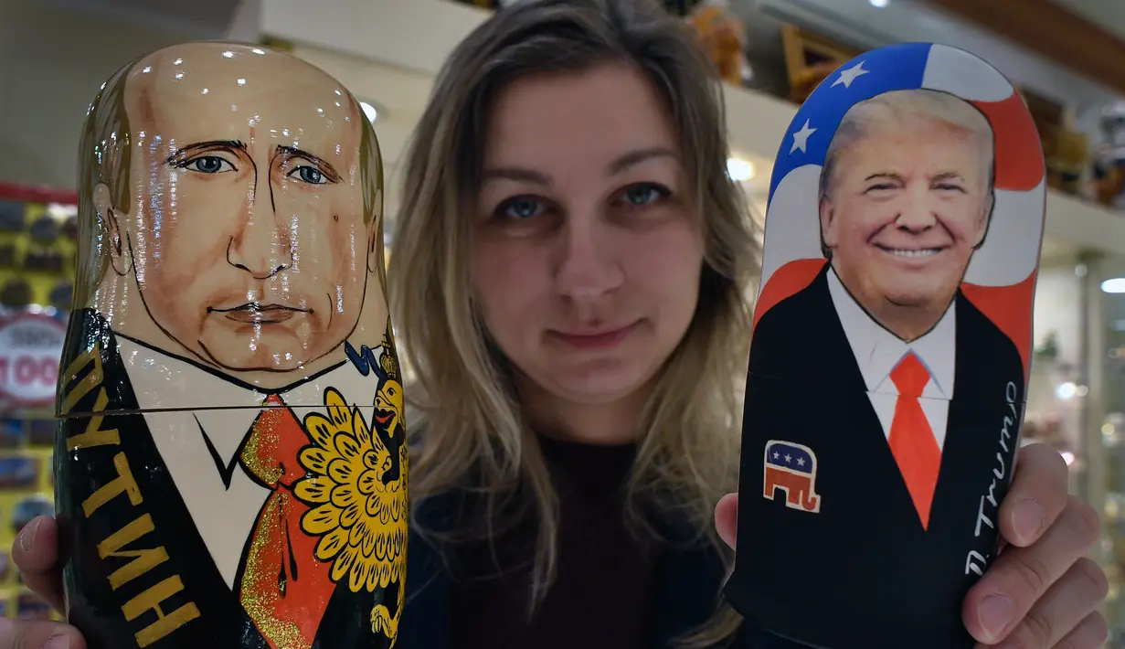 Seorang penjaga toko menunjukan Matryoshka yang berkarakter Presiden Rusia, Vladimir Putin dan Presiden Amerika Serikat terpilih Donald Trump di Moskow, Rusia (16/1). (AFP/Alexander Nemenov)
