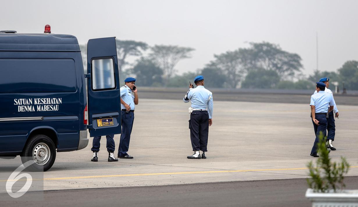 Petugas berjaga di belakang mobil menunggu kedatangan jenazah korban jatuhnya Pesawat Hercules C-130 yang akan tiba di Lanud Halim, Jakarta, Rabu (1/7/2015). Peristiwa nahas tersebut merenggut sekitar 122 korban jiwa. (Liputan6.com/Faizal Fanani)