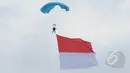 Aksi terjun payung prajurit TNI AU membawa bendera merah putih saat peringatan HUT ke-69 TNI AU Tahun 2015 di Lanud Halim Perdanakusuma, Jakarta, Kamis (9/4/2015). Acara tersebut menampilkan demo darat dan atraksi udara. (Liputan6.com/Herman Zakharia)