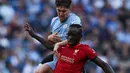 Pemain Manchester City John Stones (kiri) berebut bola dengan pemain Liverpool Sadio Mane pada pertandingan sepak bola semifinal Piala FA di Stadion Wembley, London, Inggris, 16 April 2022. Liverpool menang 3-2. (Adrian DENNIS/AFP)