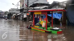 Pedagang Ketoprak menerobos banjir di kawasan Pasar Buncit, Jakarta Selatan, Selasa (9/2/2016). Banjir menggenangi kawasan tersebut hingga setinggi 100 cm akibat luapan Kali Kemang. (Liputan6.com/Gempur M Surya)